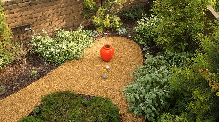 Photo of a drought-tolerant garden 与 a planter in 的 middle of 的 garden path.